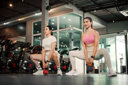 Two Young Asian woman exercise workout at gym fitness training sport with kettlebell weight lifting.の写真素材