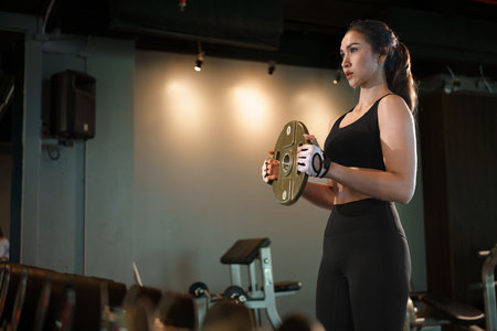 Sporty woman doing exercises with heavy weights plates in gym.の写真素材