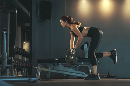 Sporty woman exercising with weight plate in the gym.の写真素材