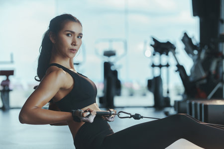 Sporty woman exercising on multistation at gym for arm and shoulders muscles. Fitness exercising in gym.の写真素材