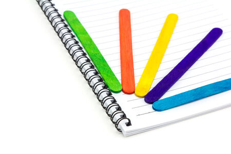 Colorful wood ice-cream stick  on Paper note book  on white backgroundの写真素材