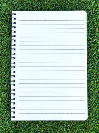 Paper note book  put on Grass backgroundの写真素材