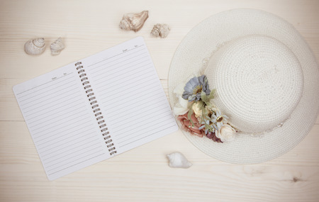 Hat bamboo weave decorated with flowers,shellfish and note book on wood backgroundの写真素材