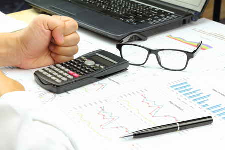 Businessman show hand boot power and Summary report finance capital market with calculate about cost at table office office.の写真素材