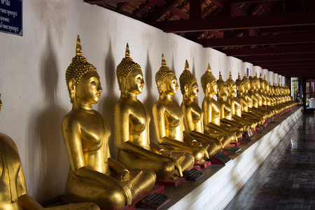 row of golden Buddha statues at a thai templeのeditorial素材