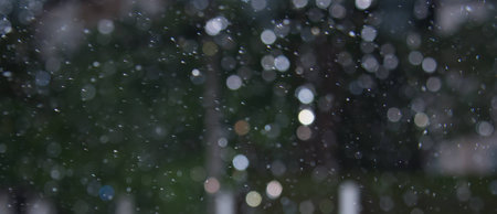Bokeh of rain with splashing moving water drop particles, dark backgroundの写真素材
