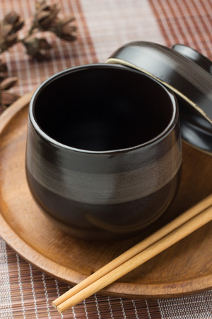 Black cup of tea with steam on wooden trayの写真素材