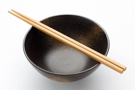 Chopsticks and black bowl isolated on whiteの写真素材