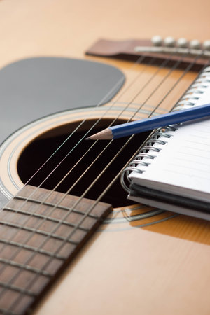 Notebook and pencil on guitar, Writing music