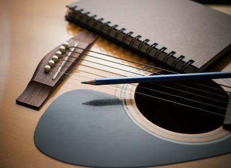 Notebook and pencil on guitar, Writing musicの写真素材