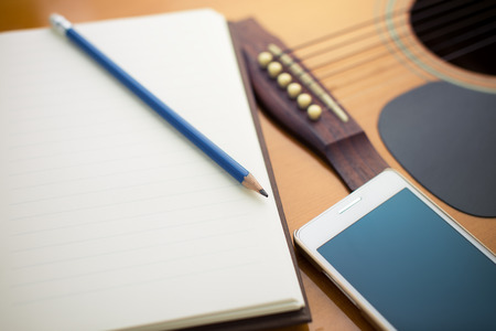 Notebook and pencil on guitarの写真素材