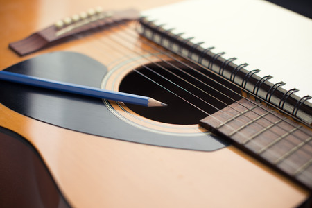 Notebook and pencil on guitar Writing musicの写真素材