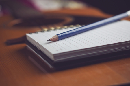 Notebook and pencil on guitar,Writing musicの写真素材