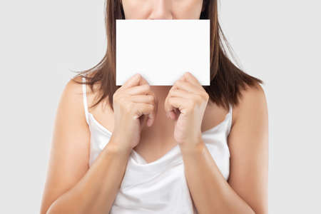 A Woman in white satin dress holding a white blank paper against a light gray background.