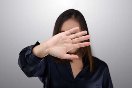 Woman in black suit showing her denial with no on her hand against gray backgroundの写真素材
