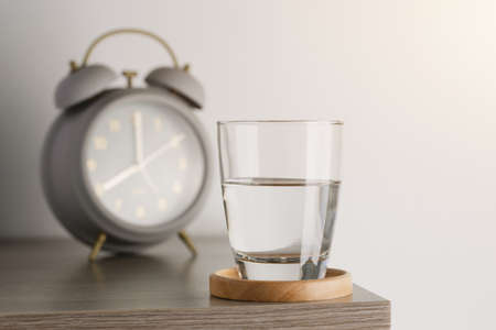 Transparent glass with water on a wooden table in the room. Drinking clear water in the morning for...