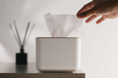 A hand pulling a tissue out of the white boxの写真素材