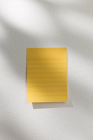 Yellow note on white wall background.の写真素材