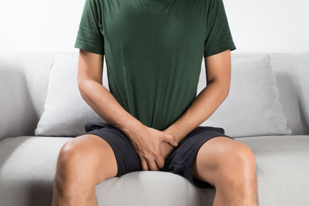 Asian man wants to pee and is holding his bladder.