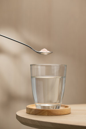 A spoon of Himalayan salt is being added to a glass of drinking water, highlighting its potential health benefits.の写真素材
