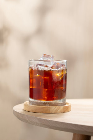 A glass of iced Americano coffee with crystal ice cubes on a wooden table, perfect for coffee lovers...