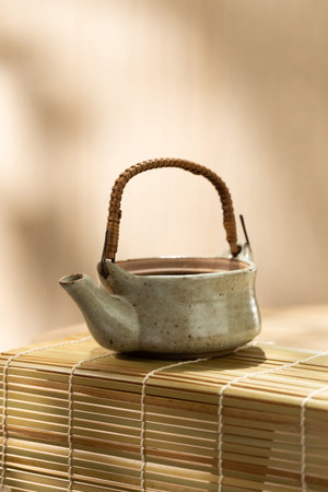 Vertical image of a traditional Japanese ceramic teapot on a bamboo mat, soft neutral tones and ample copy space above and below for branding or editorial design.の写真素材