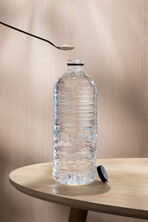 Pouring pink Himalayan salt into a water bottle to add natural minerals for healthy hydration and...