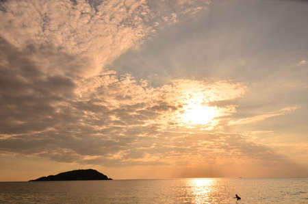 Beautiful sunset above the sea.Gold Sunset, sea and clouds. Beautiful golden orange sunset over the ocean. The sun sets turning the sky yellow, orange & red tones & reflects in the ocean.の写真素材