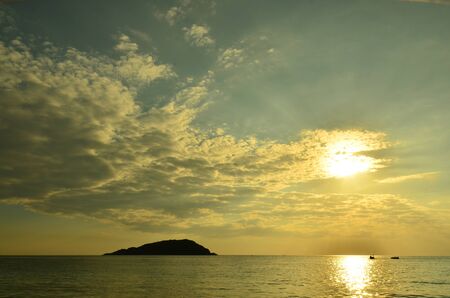 Beautiful sunset above the sea.Gold Sunset, sea and clouds. Beautiful golden orange sunset over the ocean. The sun sets turning the sky yellow, orange & red tones & reflects in the ocean.の写真素材