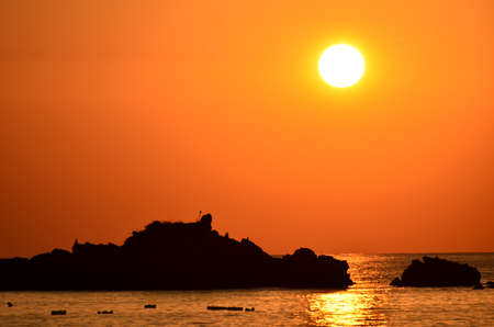 Beautiful sunset above the sea.Gold Sunset, sea and clouds. Beautiful golden orange sunset over the ocean. The sun sets turning the sky yellow, orange & red tones & reflects in the ocean.の写真素材