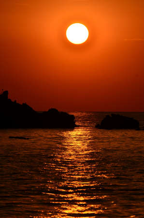Beautiful sunset above the sea.Gold Sunset, sea and clouds. Beautiful golden orange sunset over the ocean. The sun sets turning the sky yellow, orange & red tones & reflects in the ocean.の写真素材