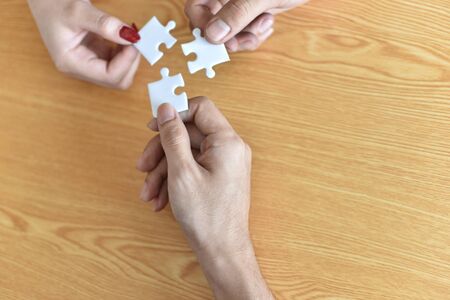 Close up of hand placing the last jigsaw puzzle piece, Hand holding missing conceptual of problem solving, finding a solution.Collaboration and business exchanges, cash, brain, dedicated team managemeの写真素材