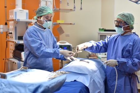Team surgeon at work in operating room. Surgical light in the operating room. Preparation for the beginning of surgical operation with a cut. The surgeon is performing surgery on the patient.の写真素材
