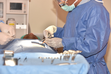 Team surgeon at work in operating room. Surgical light in the operating room. Preparation for the beginning of surgical operation with a cut. The surgeon is performing surgery on the patient.の写真素材