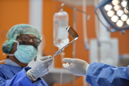 Team surgeon at work in operating room. Surgical light in the operating room. Preparation for the beginning of surgical operation with a cut. The surgeon is performing surgery on the patient.の写真素材