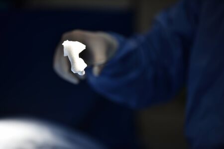 Team surgeon at work in operating room. Surgical light in the operating room. Preparation for the beginning of surgical operation with a cut. The surgeon is performing surgery on the patient.の写真素材