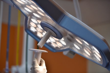 Team surgeon at work in operating room. Surgical light in the operating room. Preparation for the beginning of surgical operation with a cut. The surgeon is performing surgery on the patient.の写真素材