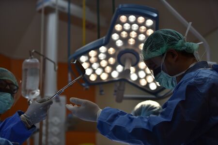 Team surgeon at work in operating room. Surgical light in the operating room. Preparation for the beginning of surgical operation with a cut. The surgeon is performing surgery on the patient.の写真素材