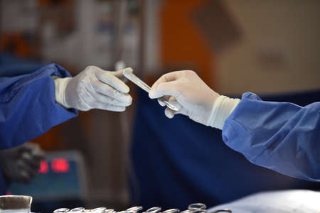 Team surgeon at work in operating room. Surgical light in the operating room. Preparation for the beginning of surgical operation with a cut. The surgeon is performing surgery on the patient.の写真素材