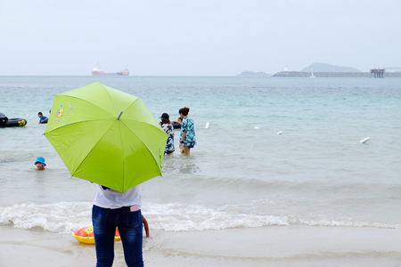 The tourists are swimming at the beach. And stroll along the sandy beach. Must use the umbrella on a rainy day with a rain storm at the beach, Sattahip, Chonburi, Thailand on April 28, 2018.のeditorial素材