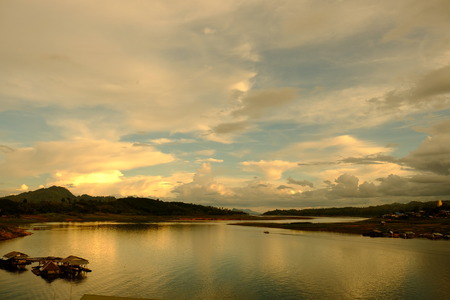The colorful sky when the sun is falling before the evening. Tourists and View of the river and surrounding communities of the dam near the Mon Bridge at Khao Laem Dam, Sangklaburi, Thailand.2018 Mayの写真素材