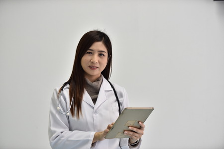 Photos of doctors in work uniforms. Photo of a young female doctor with a endoscope on her neck and a notepad with a pen in her hands. Isolated portrait of a doctor.の写真素材