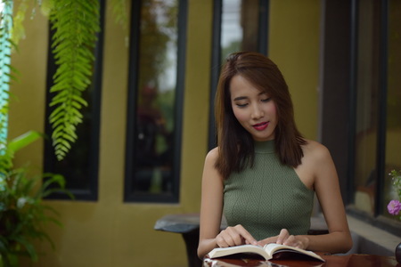 Portrait of a beautiful young woman in a coffee shop near the house. Portrait of a beautiful young woman reading a book Relaxing and comfortable.の写真素材