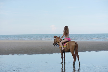 Beautiful model with beautiful horse at the beach in the evening. Before sunsetの写真素材