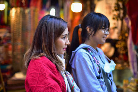 Couple of young asian women in traditional clothes looking at each other in the street marketの写真素材