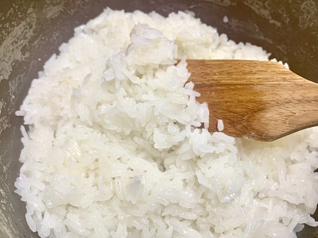The focus of scoop of white sticky rice in a pot using a spatulaの写真素材