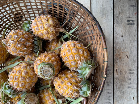 Pineapples in a basket on wooden table. Top viewの写真素材