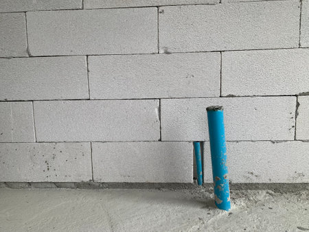 Concrete wall with blue plastic pipes and cement mortar. Construction site.の写真素材