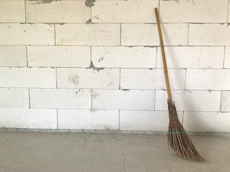 broom on the cement floor and white brick wall in the backgroundの写真素材