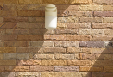 Surface of stone wall and lamp with sunlight shadow for use as background.の写真素材